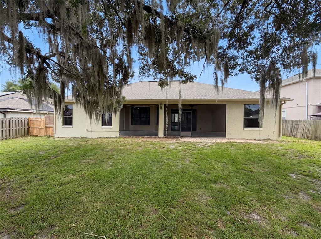 The rear exterior of a single-story house features a screened-in porch and a grassy yard — 216 BLUE CRYSTAL DRIVE, DELAND, FL