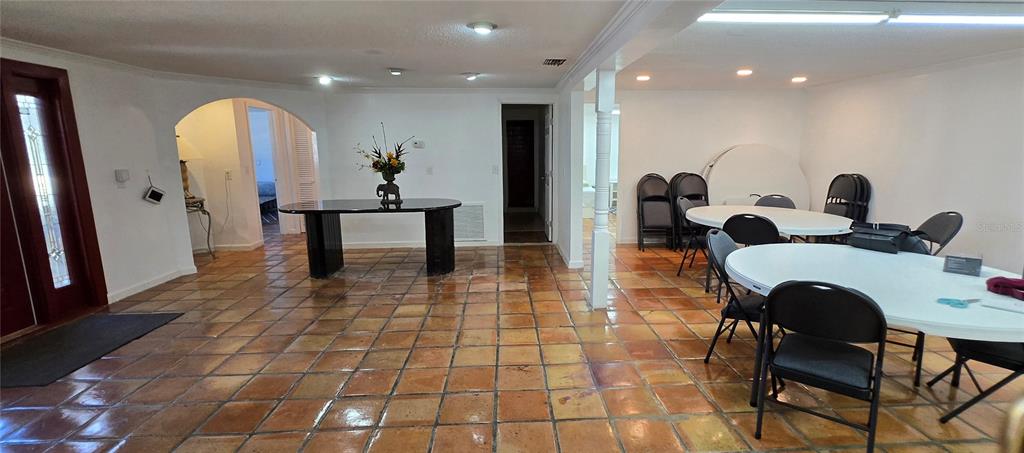A room with terracotta tile flooring, a black console table, and several folding tables and chairs — 8814 ROCKY CREEK DRIVE, TAMPA, FL