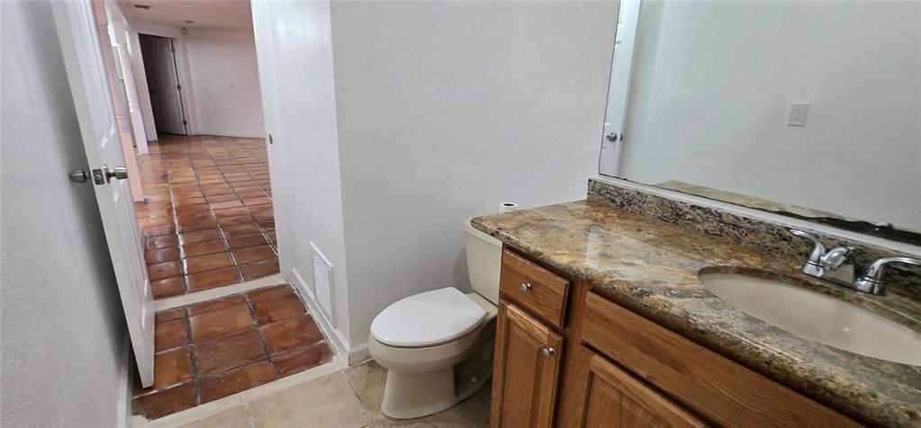 A bathroom features a granite-topped vanity, a toilet, and a doorway leading to a tiled room — 8814 ROCKY CREEK DRIVE, TAMPA, FL
