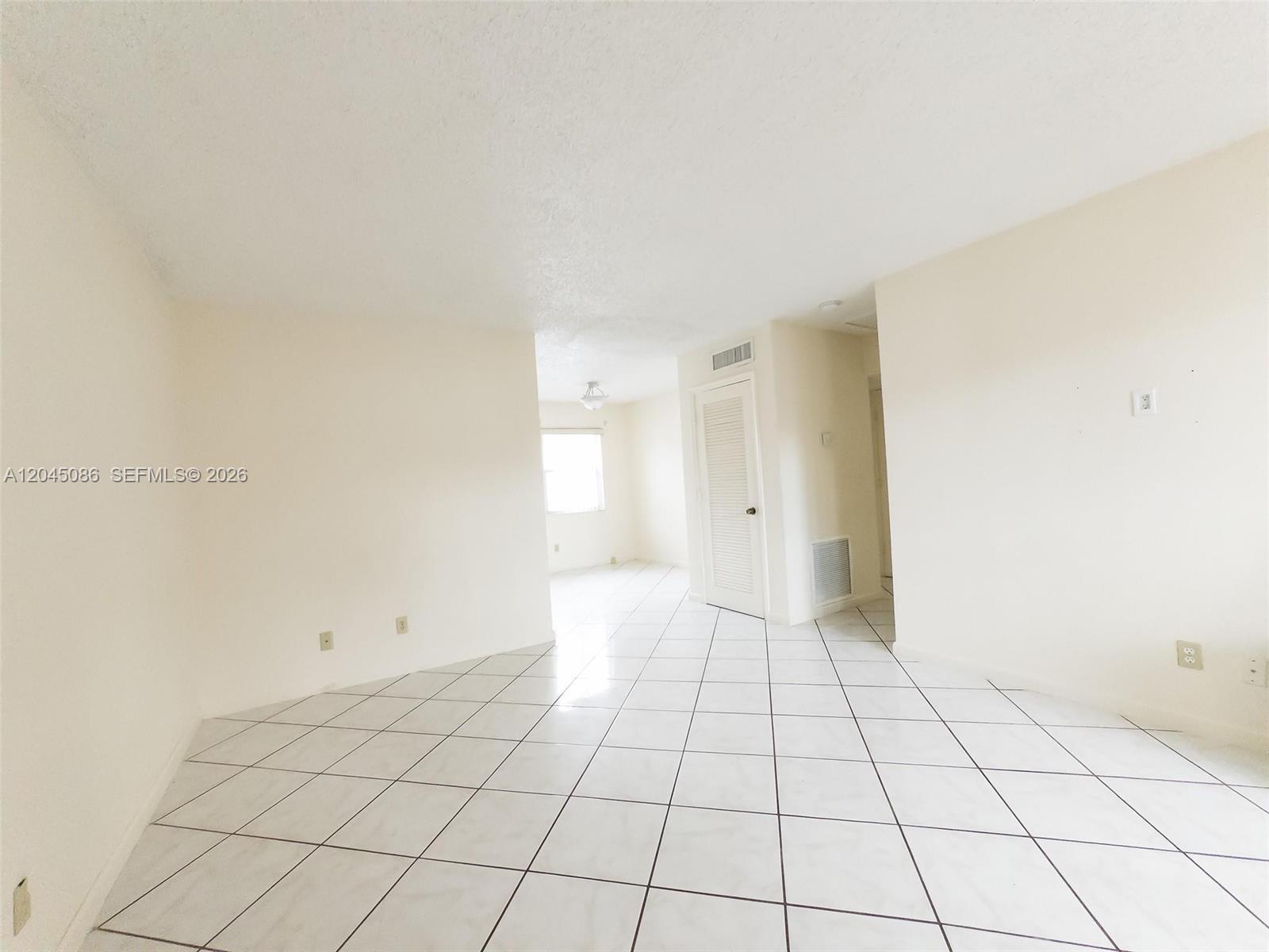 An empty room features white walls, a white tiled floor, and a closed door — 5870 NW 16th Pl # 4, Sunrise FL 33313, SUNRISE, FL