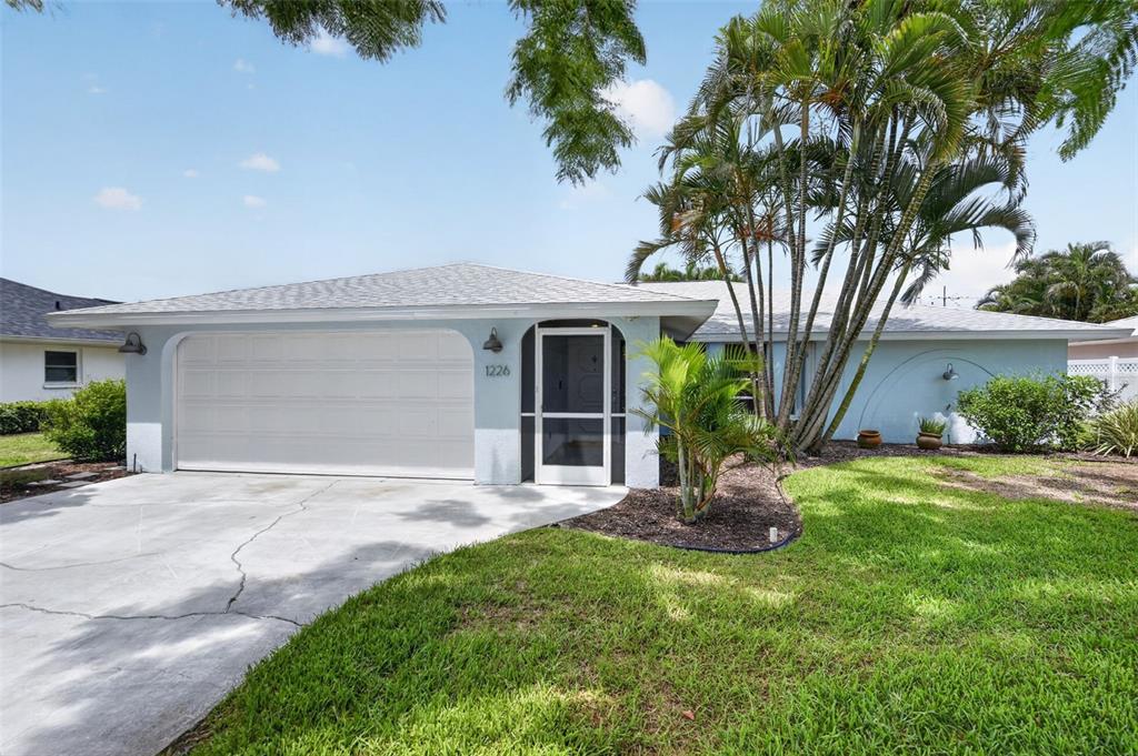 A light blue single-story house features a white garage door and a screened front entrance — 1226 PINE NEEDLE ROAD, VENICE, FL