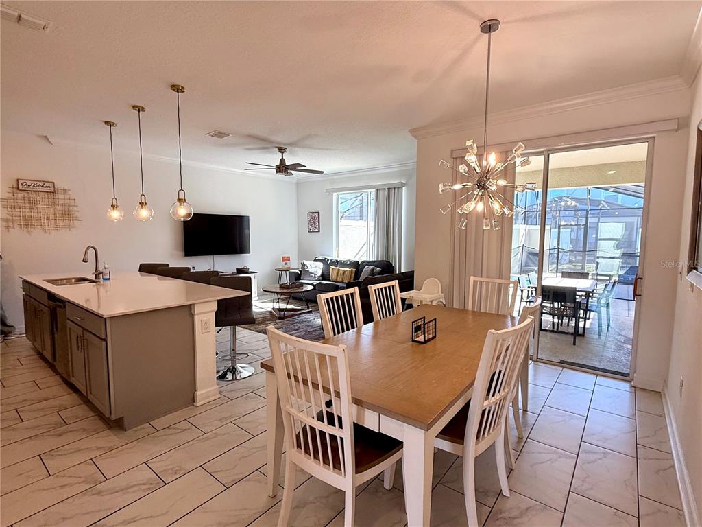 An open-concept kitchen and dining area with a large island and sliding glass patio doors — 4190 PARAGRAPH DRIVE, KISSIMMEE, FL