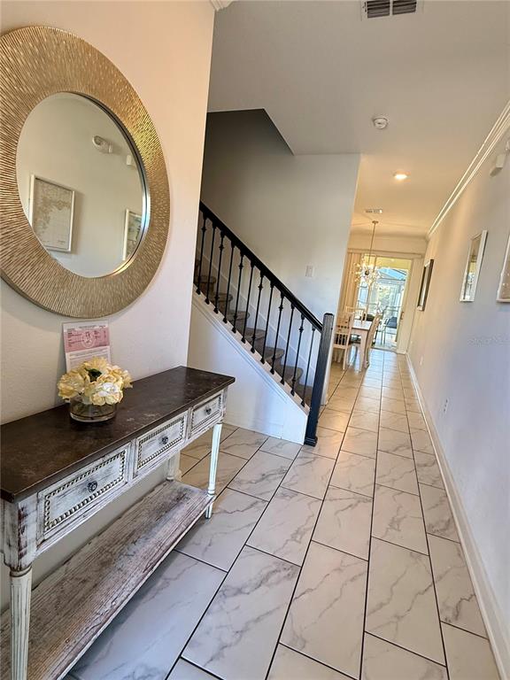 An entryway features a console table, a round mirror, and a staircase with black railings — 4190 PARAGRAPH DRIVE, KISSIMMEE, FL