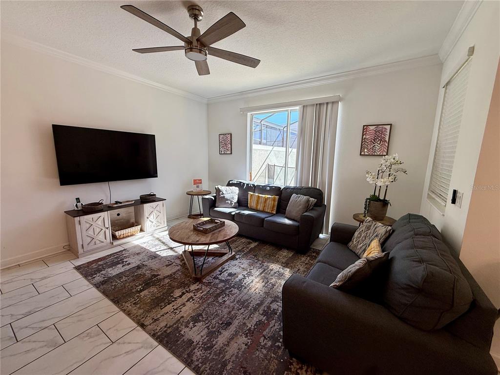 A living room features two dark sofas, a round coffee table, and a television console — 4190 PARAGRAPH DRIVE, KISSIMMEE, FL