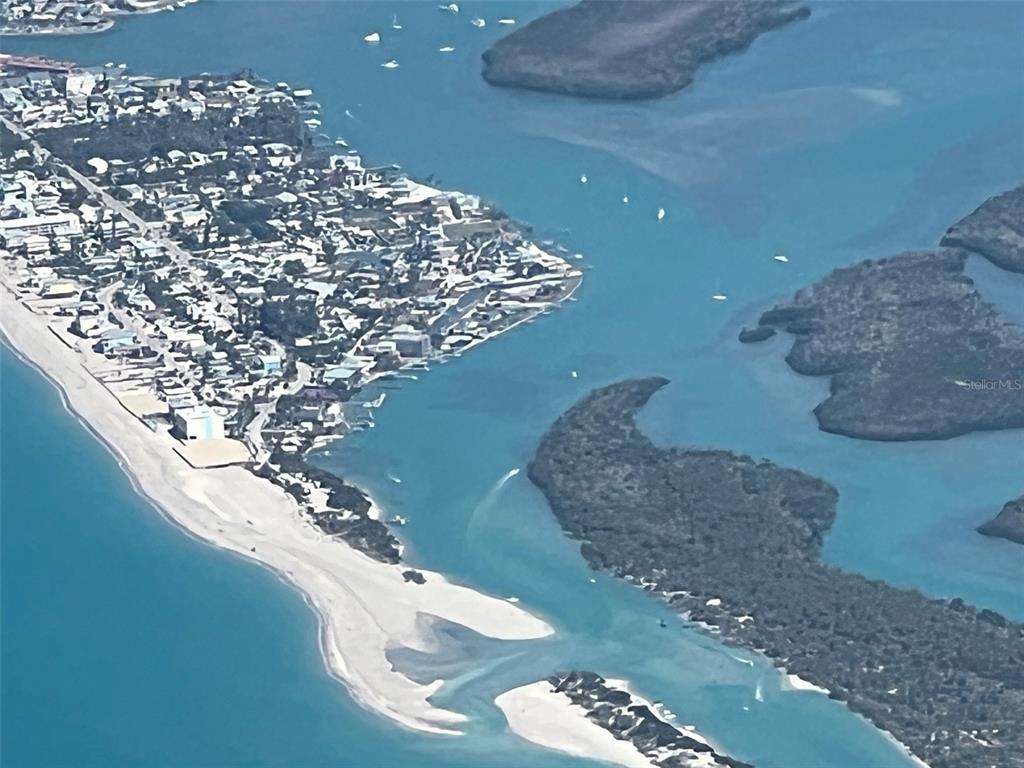 An aerial view shows a sandy beach, residential buildings, and mangrove islands surrounded by water — 1285 HOLIDAY DRIVE, ENGLEWOOD, FL