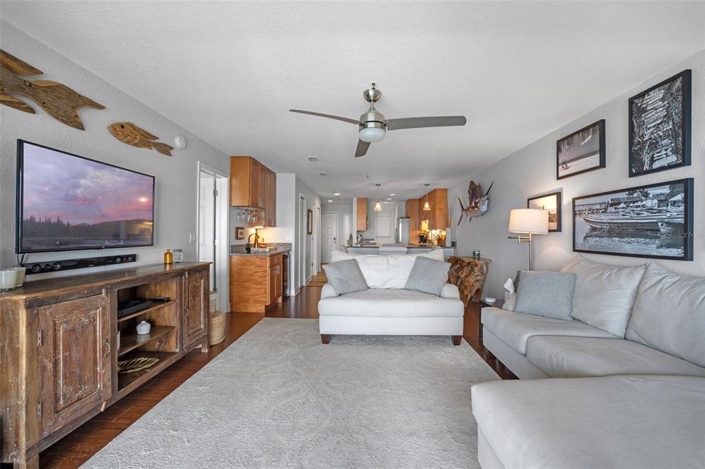 A living room features a wooden media console, a white sofa, and a ceiling fan — 442 BOUCHELLE DRIVE UNIT 203, NEW SMYRNA BEACH, FL