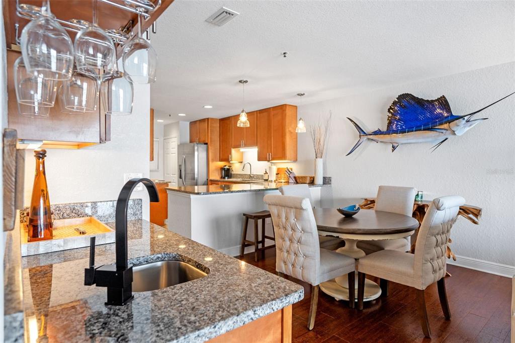 A kitchen and dining area with granite countertops, wooden cabinets, and a mounted sailfish decoration — 442 BOUCHELLE DRIVE UNIT 203, NEW SMYRNA BEACH, FL