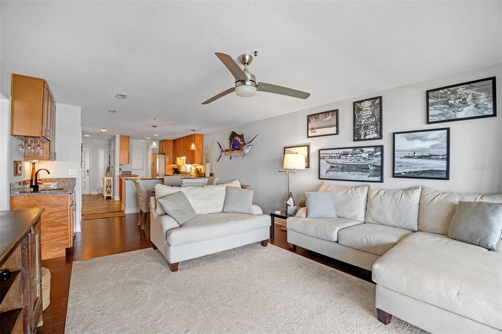 A living room features a sectional sofa, a loveseat, and an open kitchen with wood cabinets — 442 BOUCHELLE DRIVE UNIT 203, NEW SMYRNA BEACH, FL