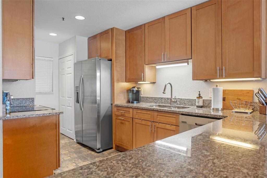 A kitchen features wood cabinets, granite countertops, stainless steel appliances, and a breakfast bar — 442 BOUCHELLE DRIVE UNIT 203, NEW SMYRNA BEACH, FL