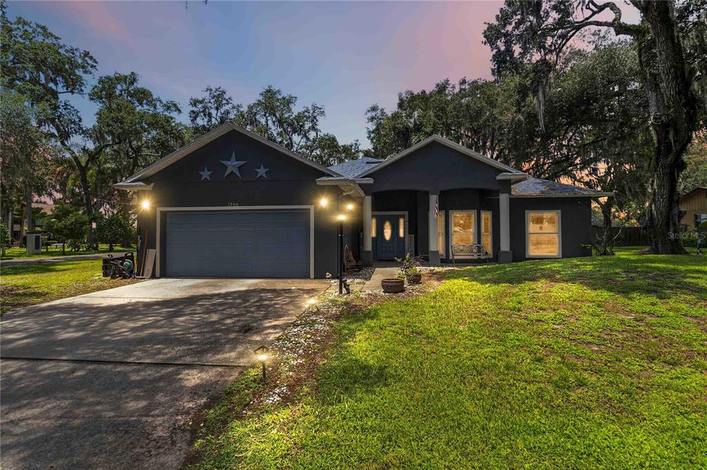 A dark gray single-story house with a two-car garage and three stars on the gable — 1260 PECAN STREET, KISSIMMEE, FL