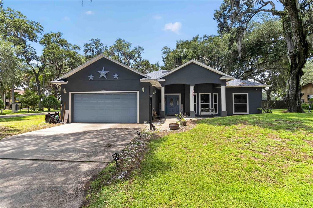 A dark gray single-story house with a two-car garage and three decorative stars above — 1260 PECAN STREET, KISSIMMEE, FL