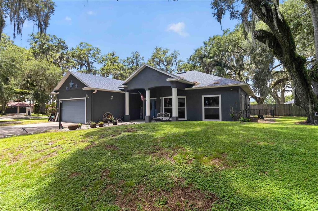 A single-story dark gray house with a front porch and attached garage sits on grass — 1260 PECAN STREET, KISSIMMEE, FL