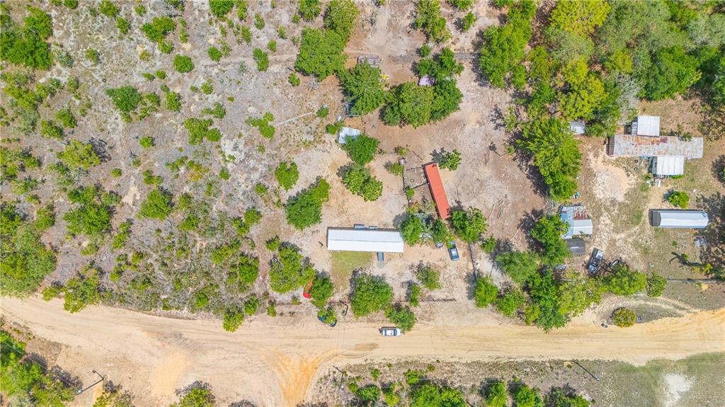 An aerial view shows a rural property with several buildings, trees, and a dirt road — 116 LONDON AVENUE, INTERLACHEN, FL