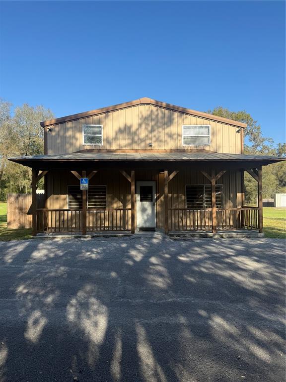 A two-story metal building with a covered front porch and a gravel parking area — 108 NW 10TH AVENUE, WILLISTON, FL