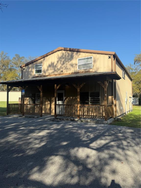 A two-story metal building with a covered front porch and a gravel parking area — 108 NW 10TH AVENUE, WILLISTON, FL