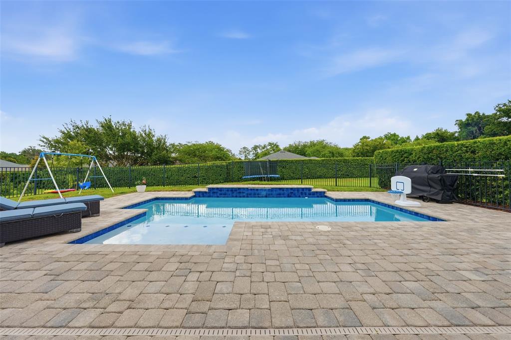 A backyard features a swimming pool with a basketball hoop and a covered patio area — 3983 SE 5TH AVENUE, OCALA, FL