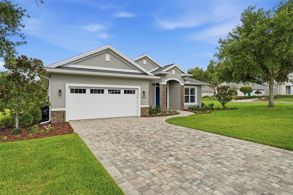 A backyard features a rectangular swimming pool with a paved deck and a covered patio — 3983 SE 5TH AVENUE, OCALA, FL