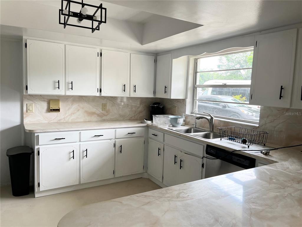 A kitchen features white cabinets, marble-patterned countertops, a double sink, and a black light fixture — 230 BAY MEADOW ROAD, LONGWOOD, FL
