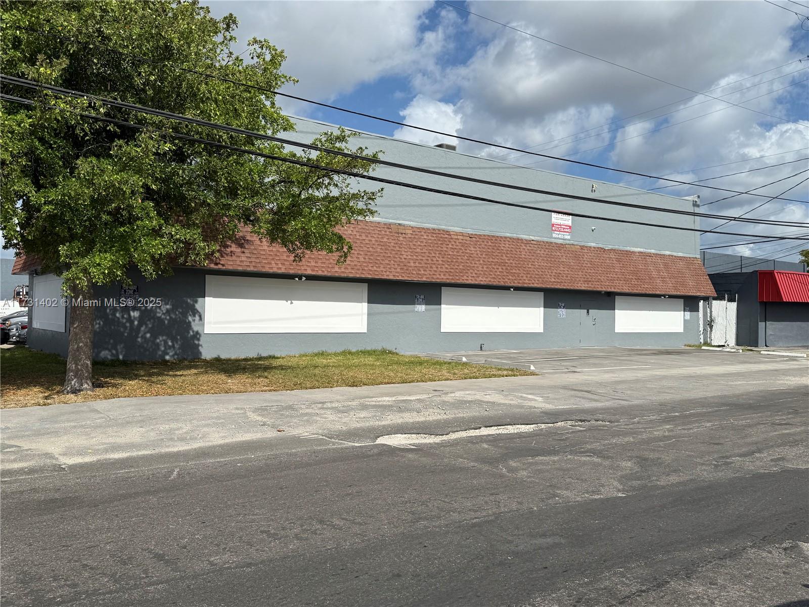 A gray commercial building with a brown shingled awning and white boarded-up windows — 5801 Plunkett St, Hollywood FL 33023, HOLLYWOOD, FL