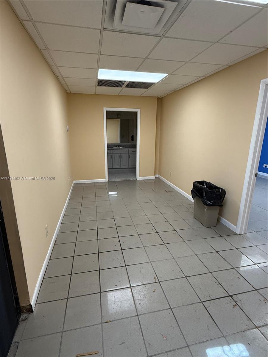 A small room with beige walls, a tiled floor, a drop ceiling, and a trash can — 5801 Plunkett St, Hollywood FL 33023, HOLLYWOOD, FL