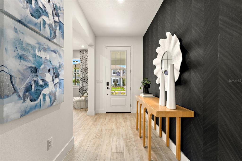 A bright entryway features light wood-look flooring, a dark accent wall, and a console table — 10248 CABANA STREET, ORLANDO, FL
