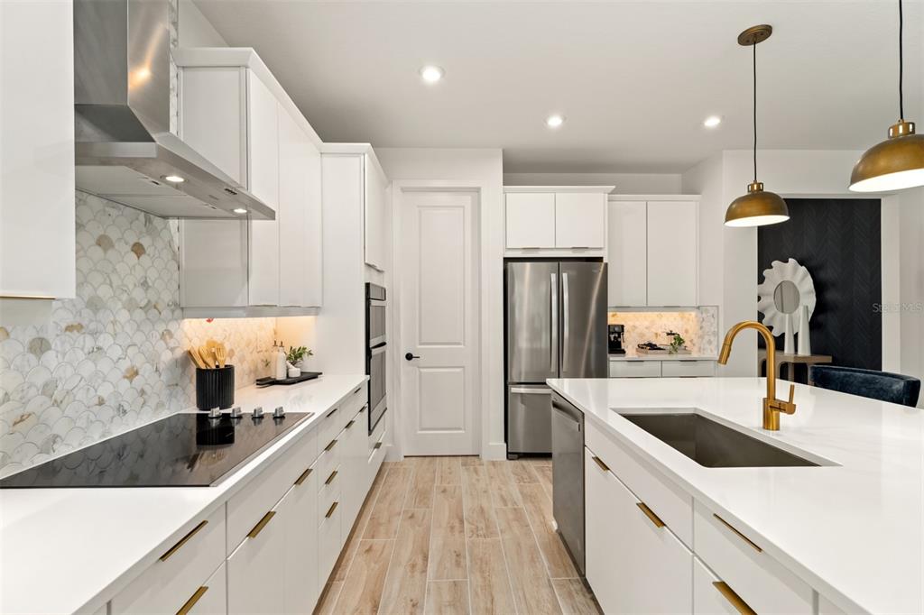A modern kitchen features white cabinetry, quartz countertops, a tile backsplash, and stainless steel appliances — 10248 CABANA STREET, ORLANDO, FL
