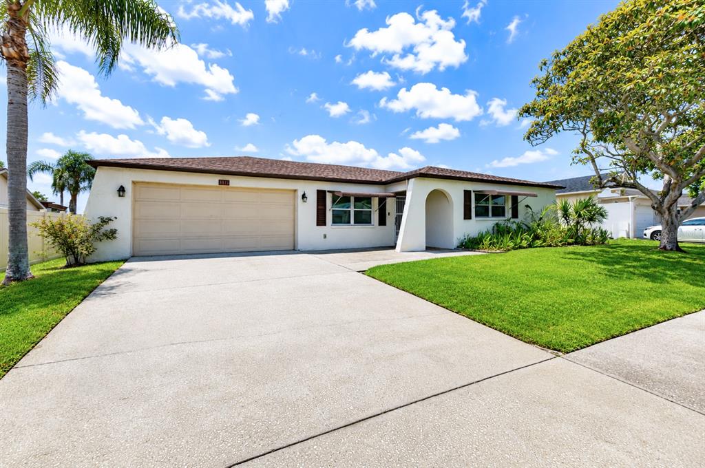 A single-story house with a beige stucco exterior, a two-car garage, and a concrete driveway — 8811 MARTINIQUE LANE, PORT RICHEY, FL