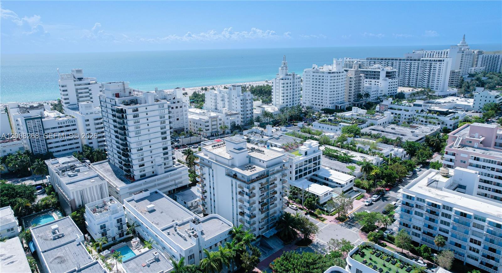 An aerial view shows multiple white high-rise buildings situated along a sandy beach and ocean — 245 18th St # 605, Miami Beach FL 33139, MIAMI BEACH, FL
