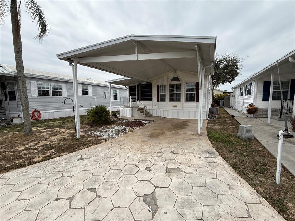 A manufactured home features a covered carport and a patterned concrete driveway — 231 ST GEORGE DRIVE, DAVENPORT, FL