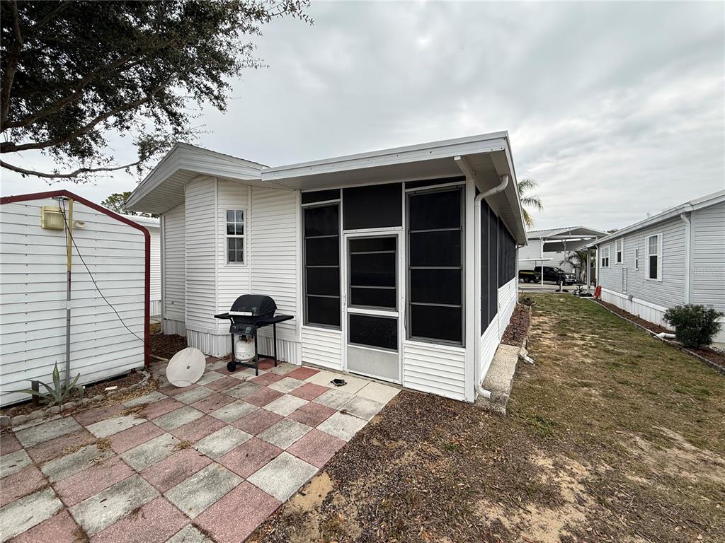 A white mobile home features a screened-in porch, a patio with checkered pavers, and a grill — 231 ST GEORGE DRIVE, DAVENPORT, FL
