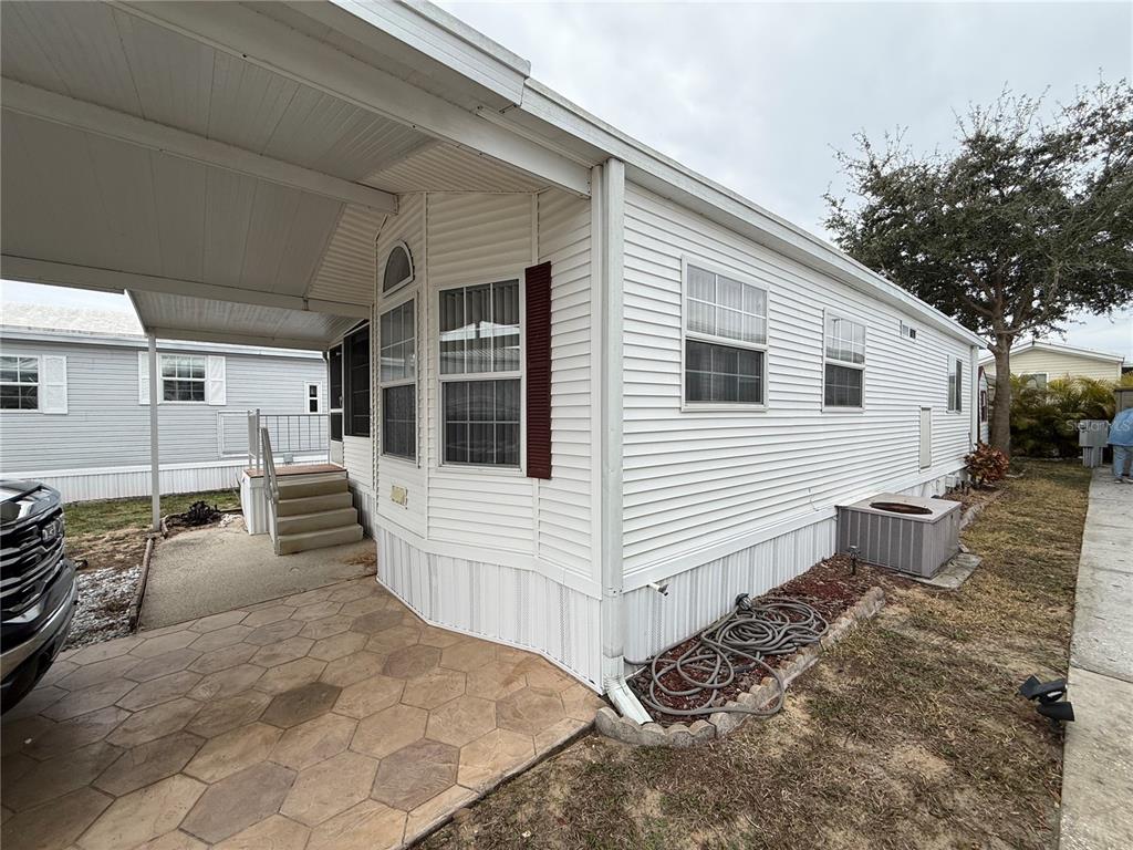 The exterior of a white mobile home features a carport, concrete patio, and stairs — 231 ST GEORGE DRIVE, DAVENPORT, FL