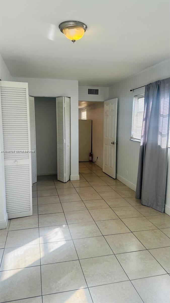 A room with light-colored tile flooring, white walls, a closet, and a doorway — 1321 NW 50th Ave # A, Lauderhill FL 33313, LAUDERHILL, FL