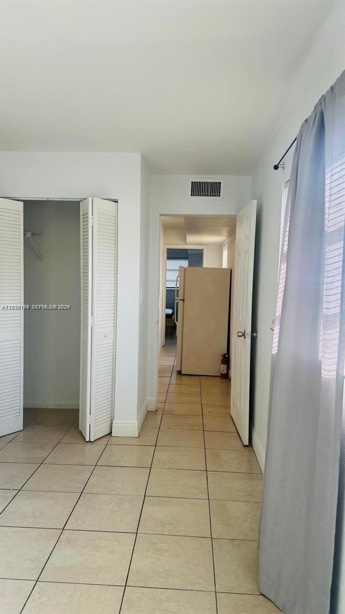 A tiled hallway connects a room with a closet to a kitchen with a refrigerator — 1321 NW 50th Ave # A, Lauderhill FL 33313, LAUDERHILL, FL
