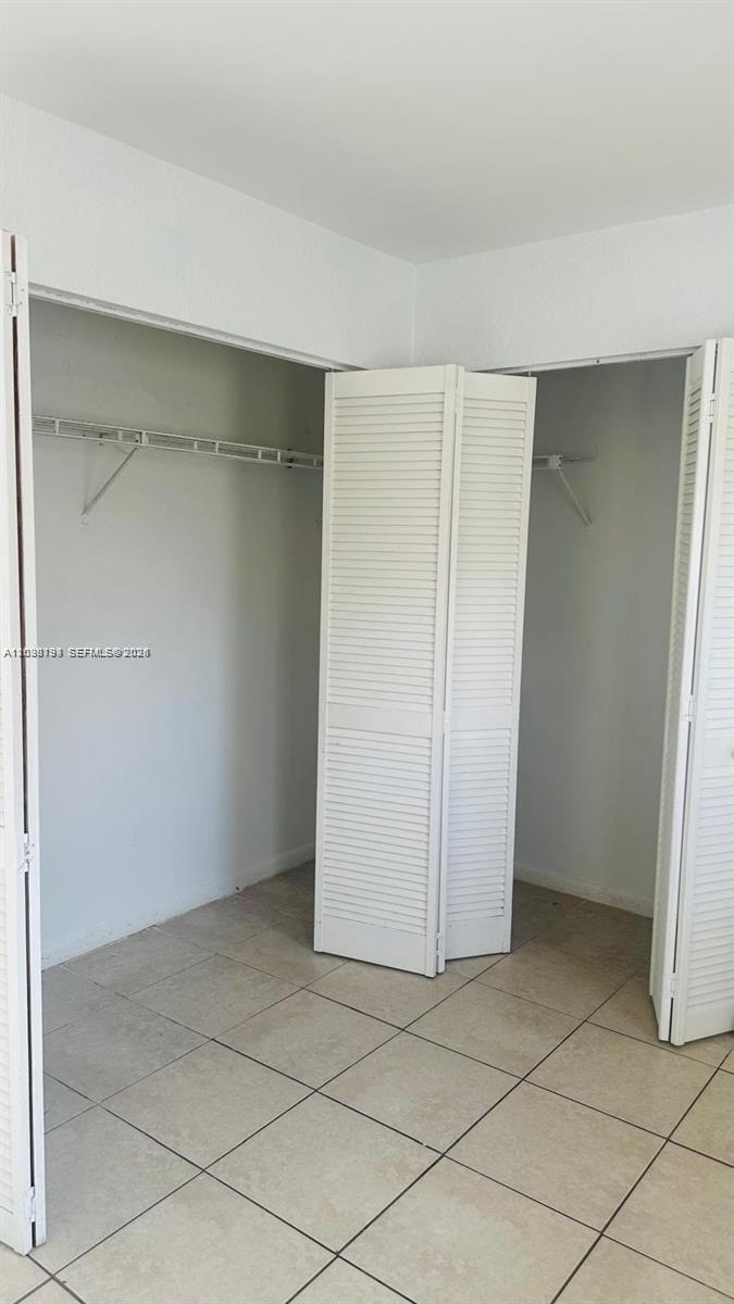 A closet with white louvered doors and wire shelving is set against a tiled floor — 1321 NW 50th Ave # A, Lauderhill FL 33313, LAUDERHILL, FL