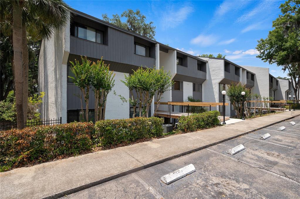 A multi-story apartment building with white stucco walls, dark gray siding, and a parking lot — 2818 SW 14TH DRIVE UNIT 107, GAINESVILLE, FL