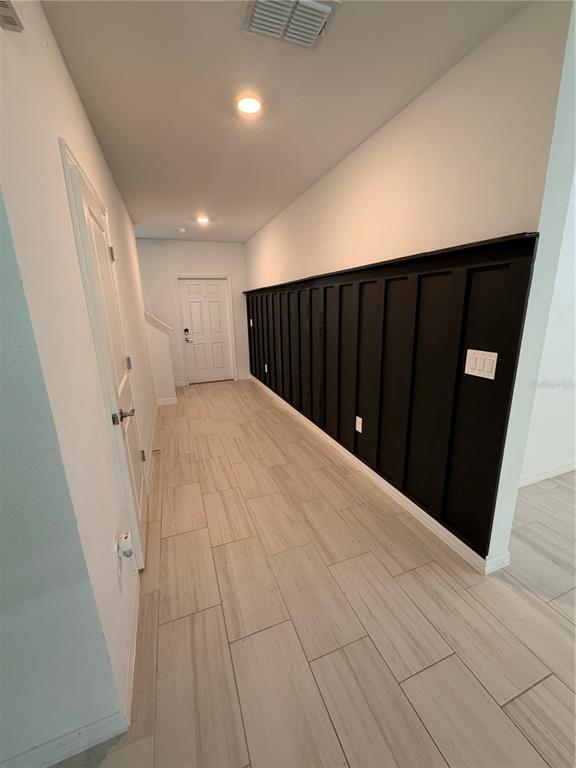 A hallway features light wood-look tile flooring and a long wall with black board-and-batten paneling — 12490 SWEET ANGEL AURA WAY, PARRISH, FL