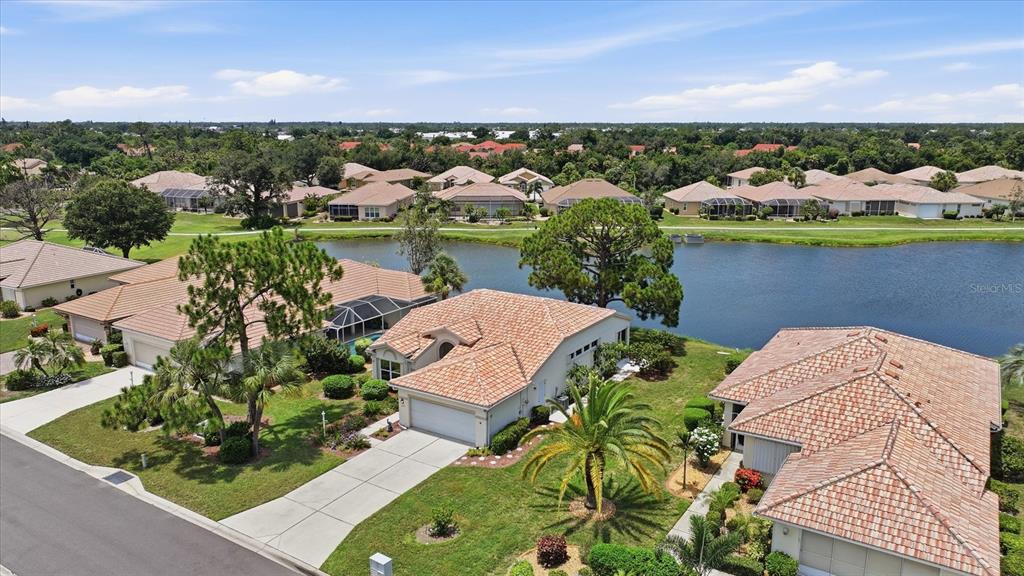 An aerial view shows several suburban houses with tile roofs situated along a small lake — 6724 GREENVIEW LANE, ENGLEWOOD, FL