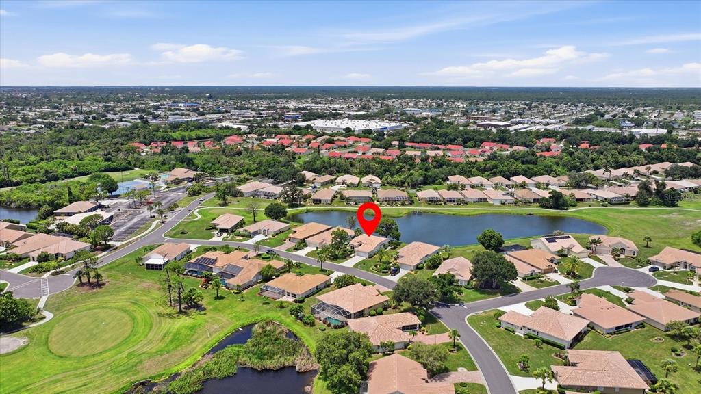 An aerial view shows a suburban neighborhood with houses surrounding a central pond — 6724 GREENVIEW LANE, ENGLEWOOD, FL