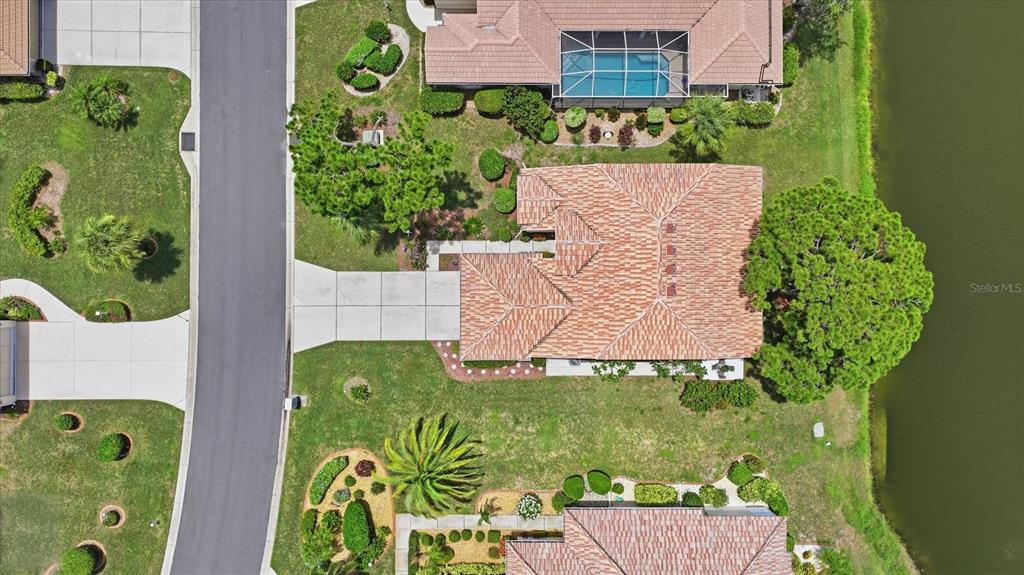 An aerial view shows a house with a tiled roof, driveway, and backyard near water — 6724 GREENVIEW LANE, ENGLEWOOD, FL