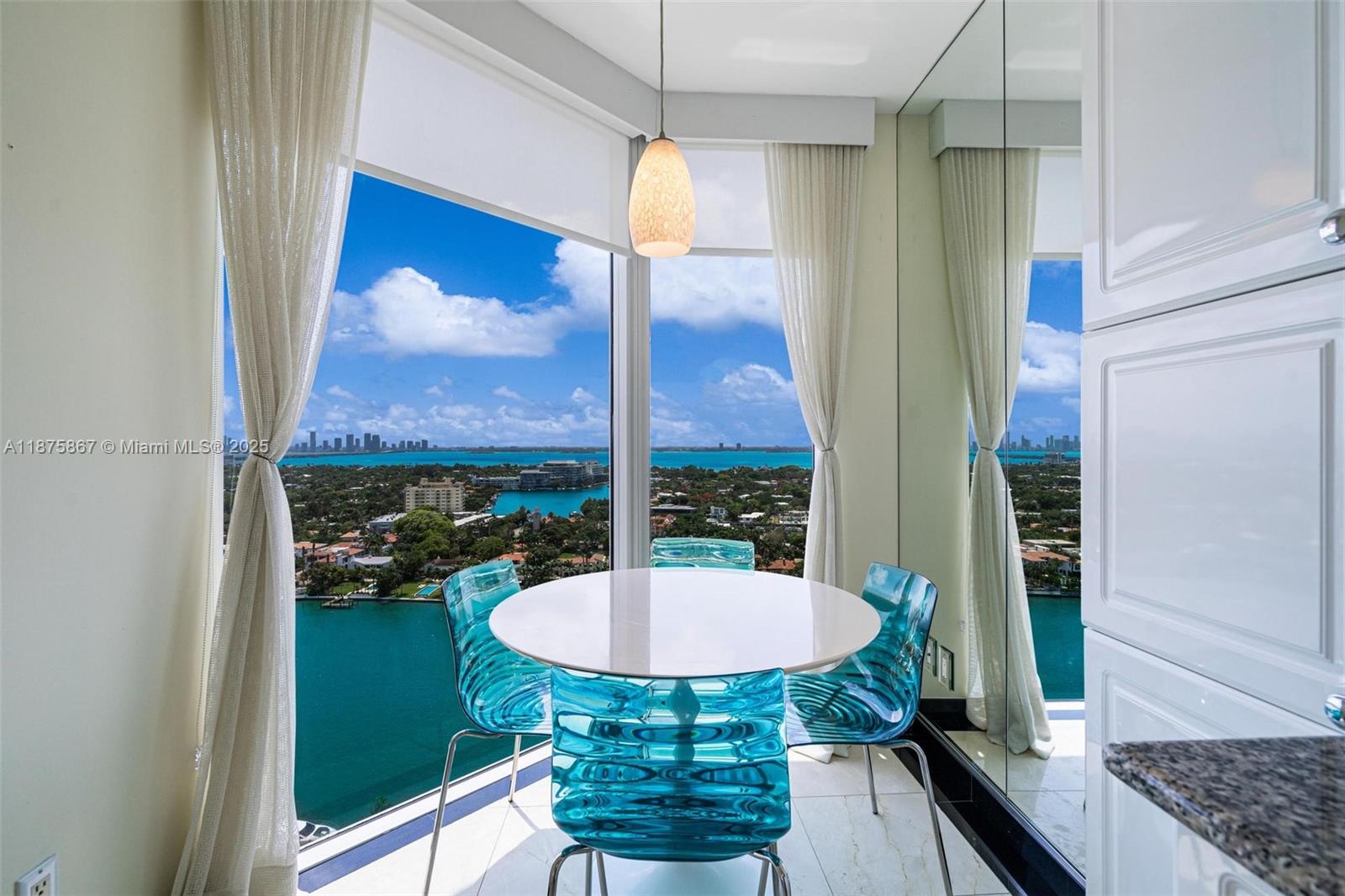 A dining area features a round white table, blue acrylic chairs, and floor-to-ceiling windows — 4779 Collins Ave # 2305, Miami Beach FL 33140, MIAMI BEACH, FL