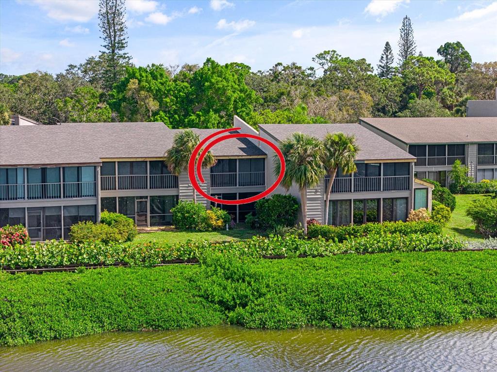 An exterior view of a multi-story apartment building with a screened balcony circled in red — 1520 PELICAN POINT DRIVE UNIT BA251, SARASOTA, FL