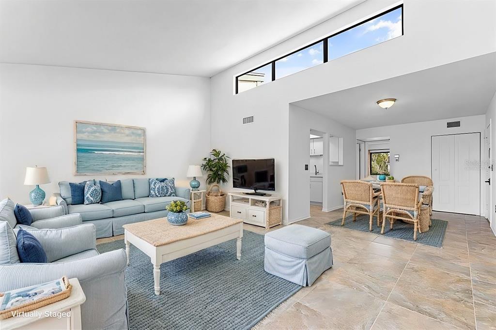 A living and dining area features vaulted ceilings, clerestory windows, and light-colored tile flooring — 1520 PELICAN POINT DRIVE UNIT BA251, SARASOTA, FL
