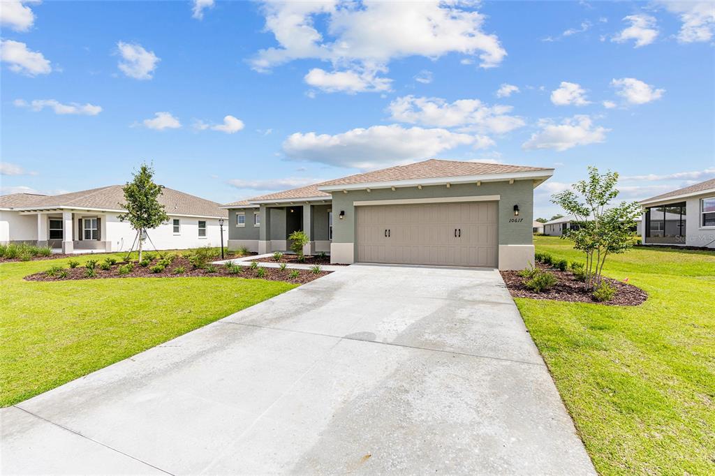 A single-story house with a tan garage, green siding, and a concrete driveway — 10617 SW 101ST LANE ROAD, OCALA, FL