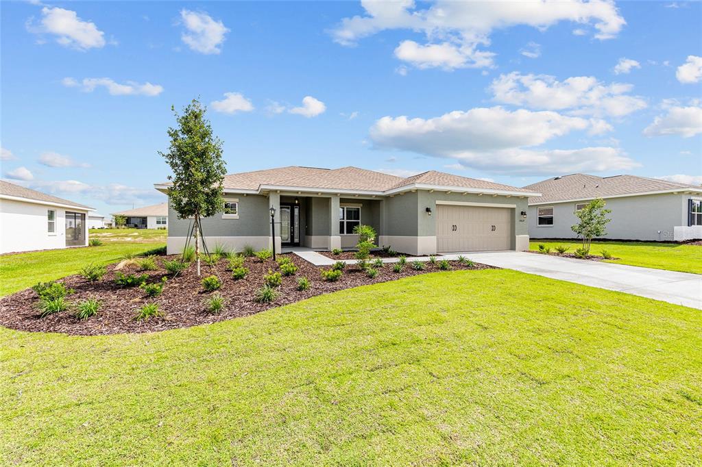 A single-story house with a tan garage, gray exterior, and a landscaped front yard — 10617 SW 101ST LANE ROAD, OCALA, FL