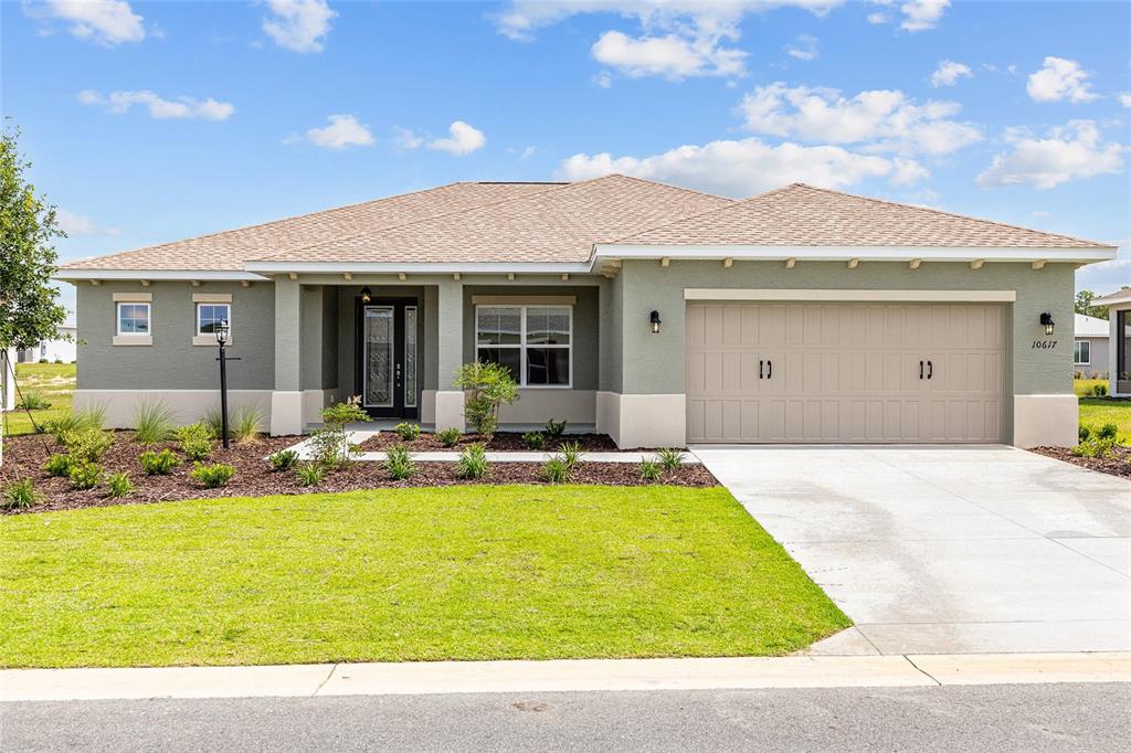 A single-story house with a green exterior, a two-car garage, and a front lawn — 10617 SW 101ST LANE ROAD, OCALA, FL