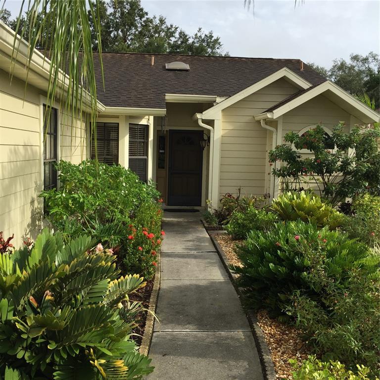 A concrete walkway leads to the front entrance of a house with light-colored siding — 5025 82ND WAY E, SARASOTA, FL