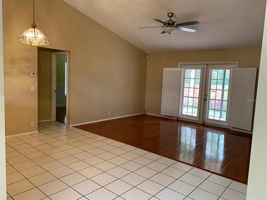 A room with a tiled floor area, a wood-floored living space, and glass patio doors — 5025 82ND WAY E, SARASOTA, FL