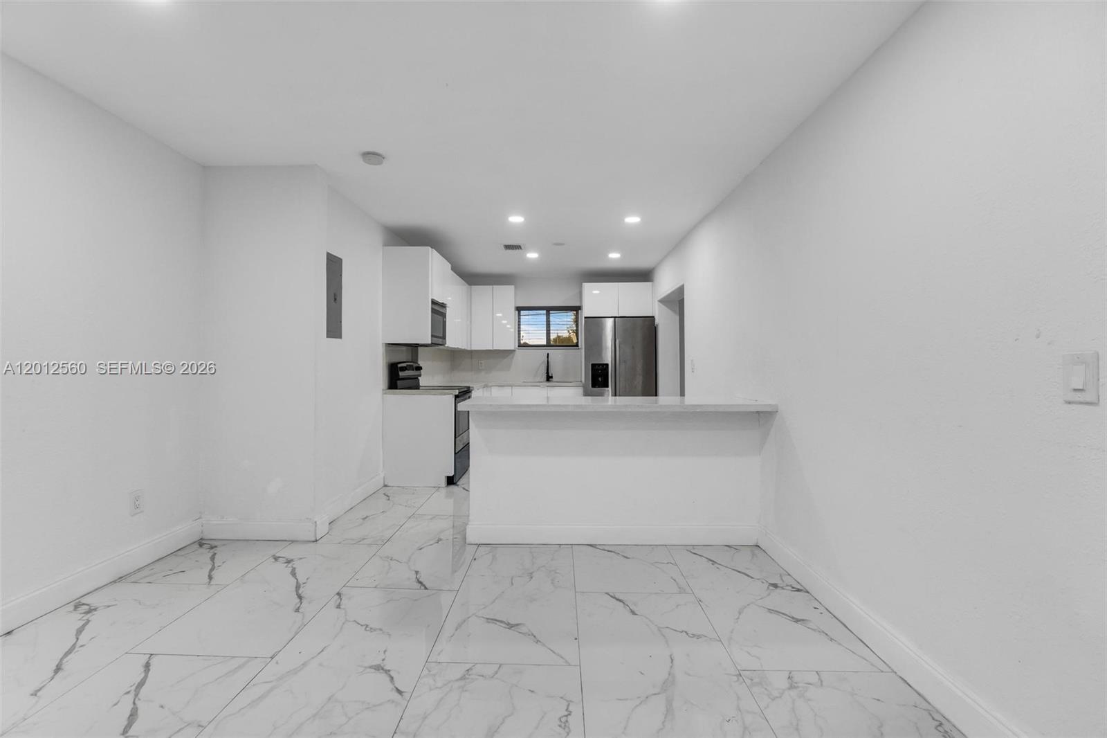 A modern kitchen features white cabinetry, stainless steel appliances, and white marble-patterned tile flooring — 4530 SW 25th St, West Park FL 33023, WEST PARK, FL