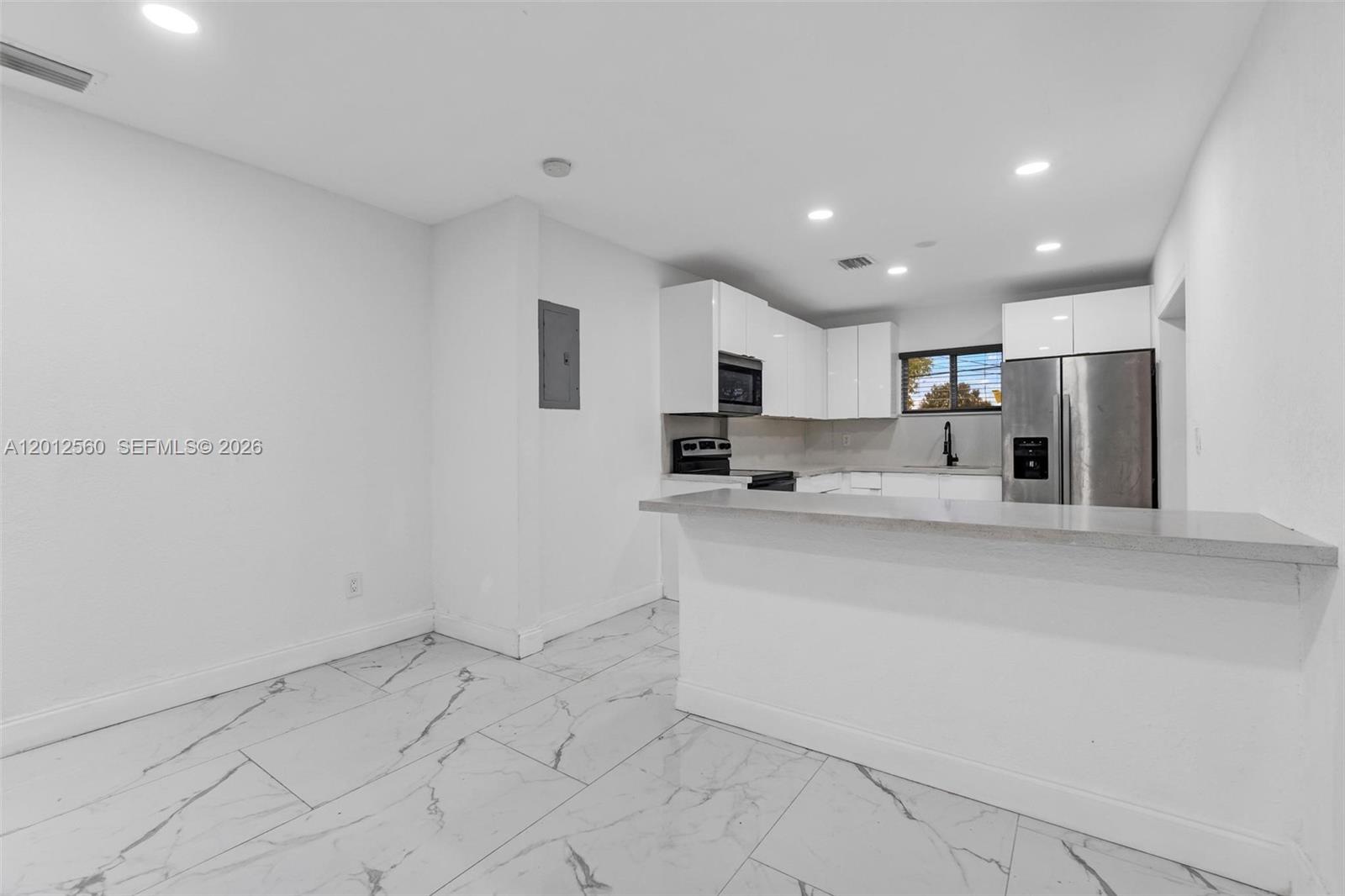 A kitchen features white cabinets, stainless steel appliances, a breakfast bar, and marble-patterned tile flooring — 4530 SW 25th St, West Park FL 33023, WEST PARK, FL