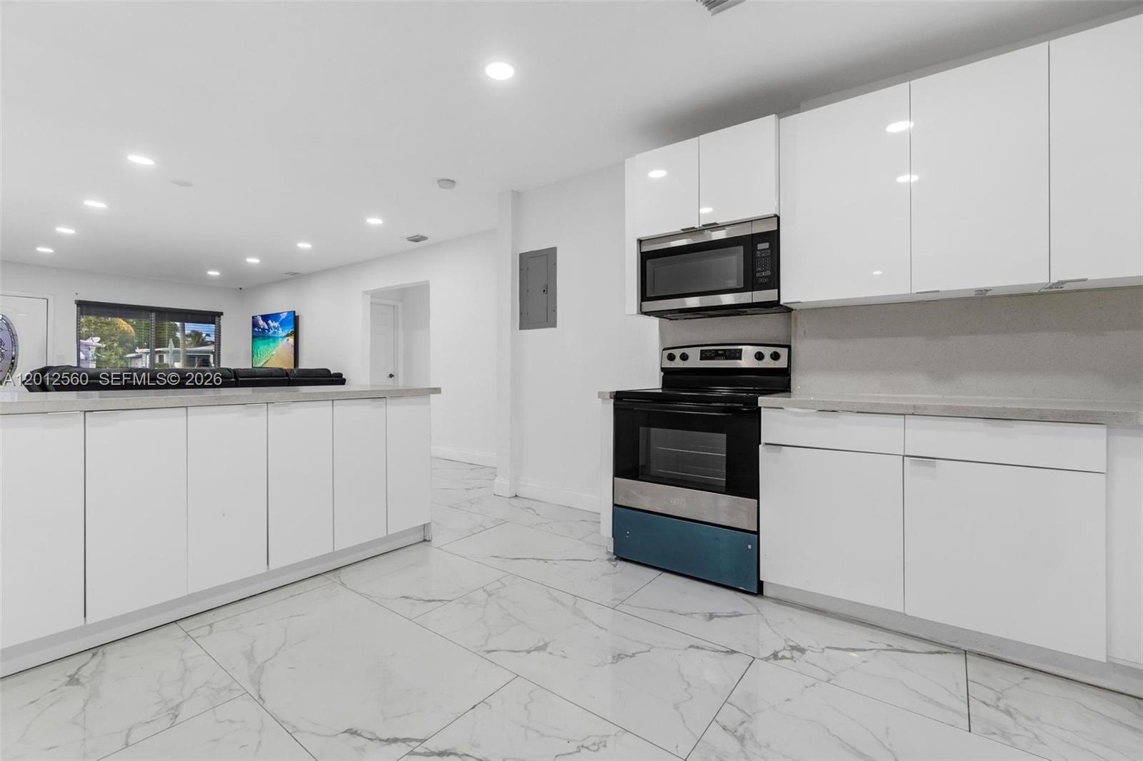A modern kitchen features white cabinets, stainless steel appliances, and white marble-patterned tile flooring — 4530 SW 25th St, West Park FL 33023, WEST PARK, FL